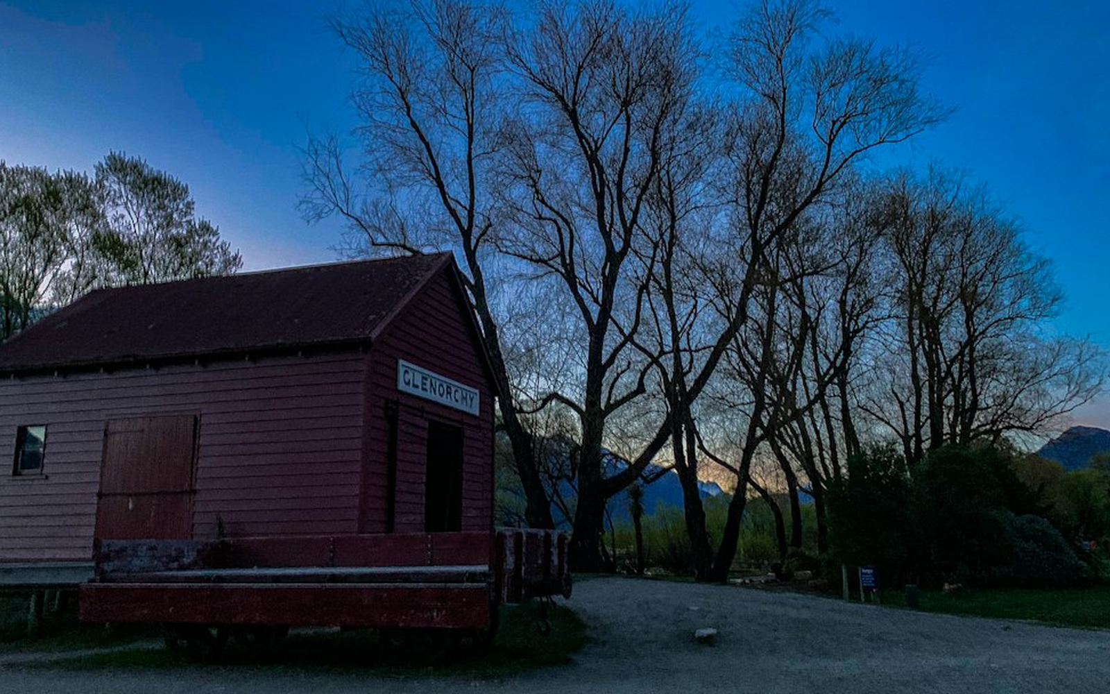 Crew carrying a folded entertainment table through a doorway at a rural New Zealand venue at dusk